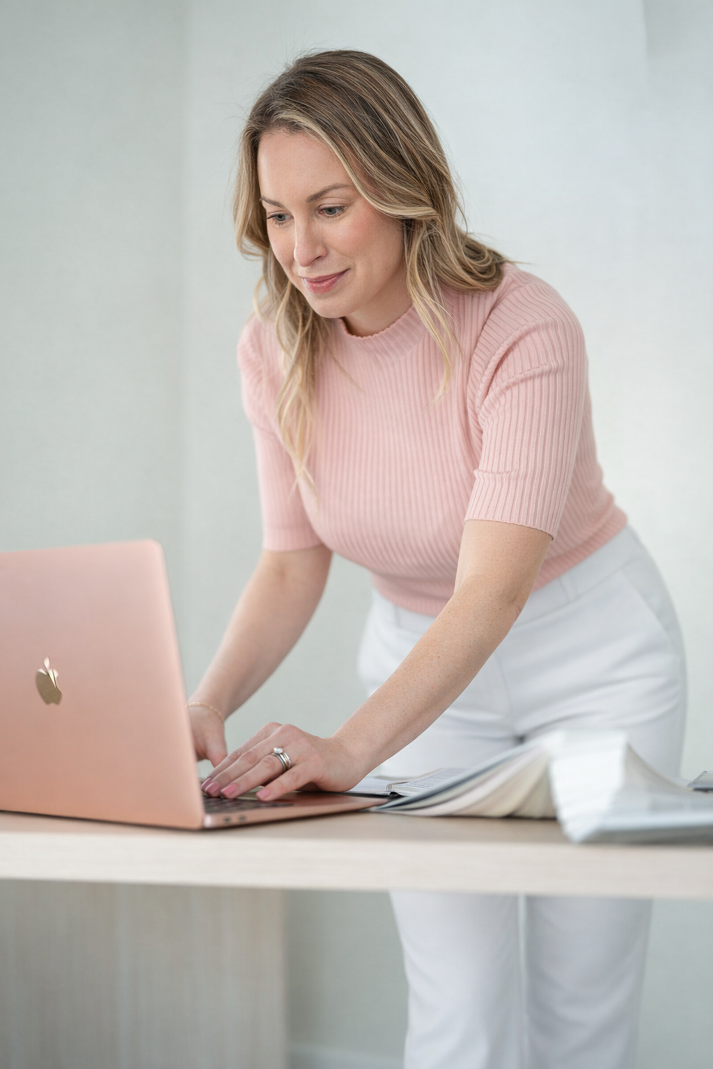 Maura Reminga working at a standing desk on a rose-gold laptop